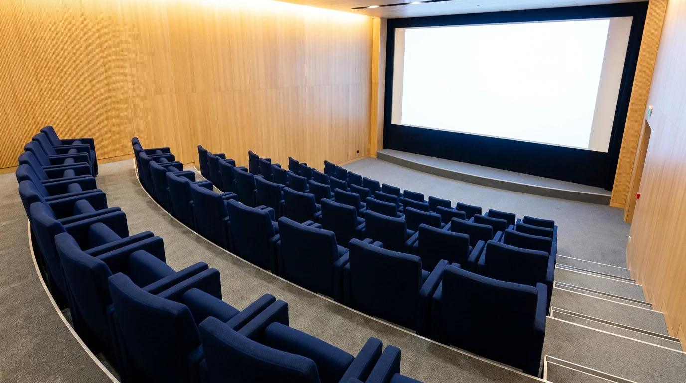 Auditorium privé avec fauteuils bleu nuit en gradins face à un écran de projection