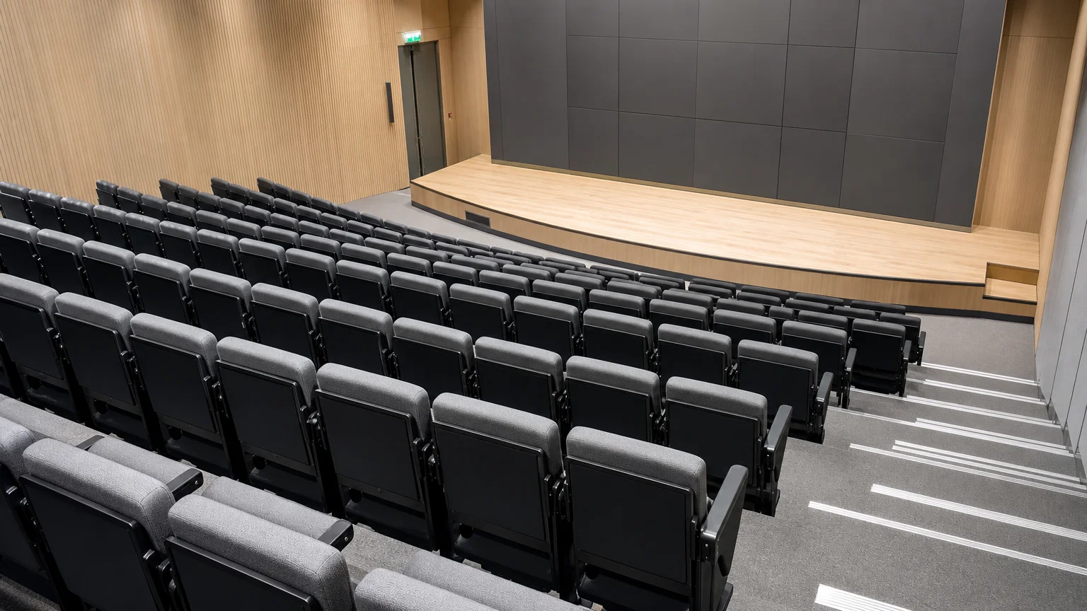 Amphithéâtre aux sièges gris équipés de tablettes écritoires, vue plongeante