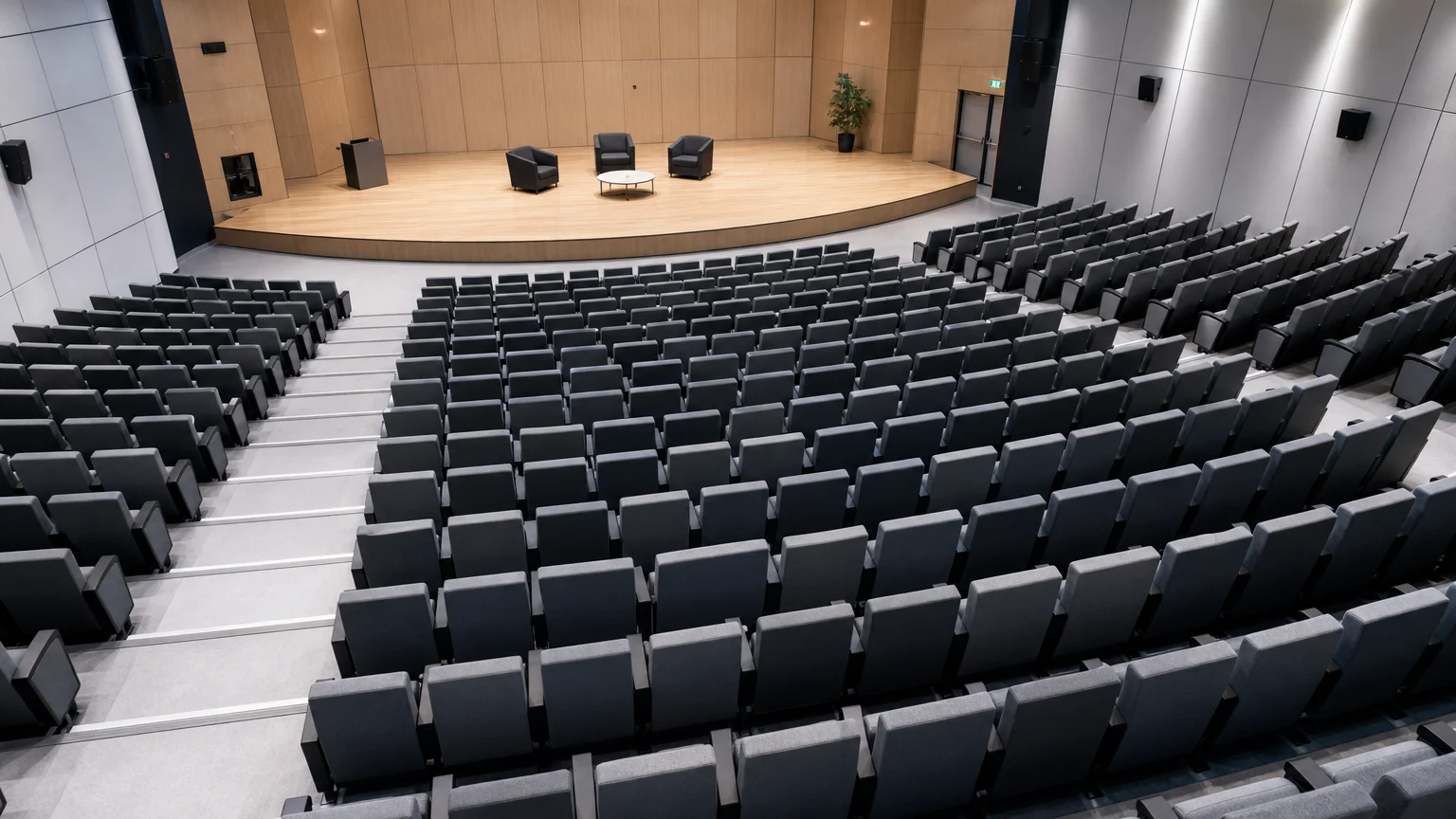 Vue en plongée sur des rangées de fauteuils gris et noirs dans un auditorium