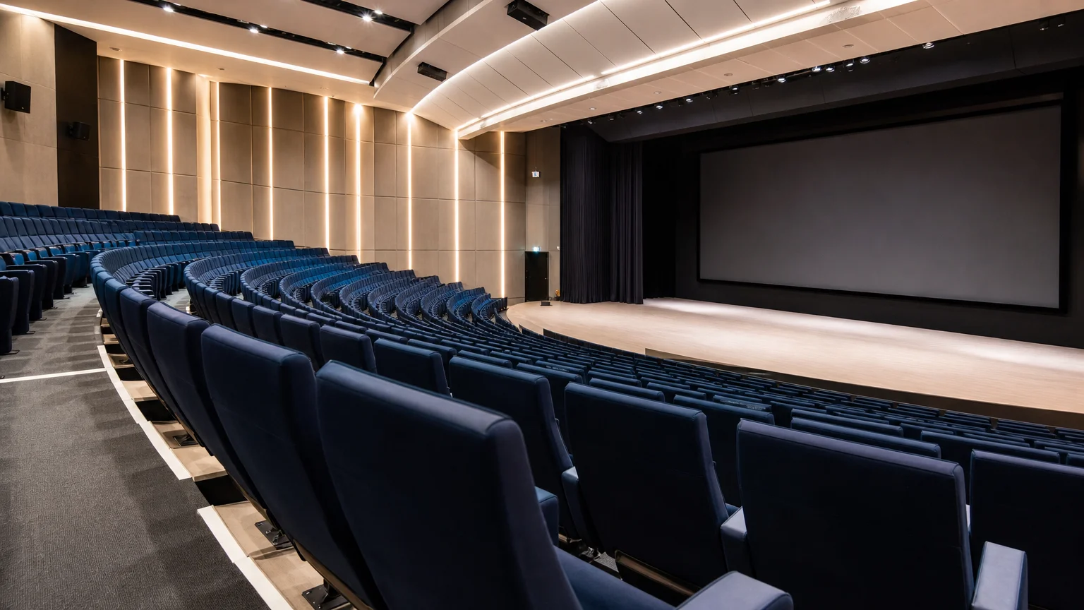 Vue latérale d’un auditorium aux fauteuils bleu nuit orientés vers la scène