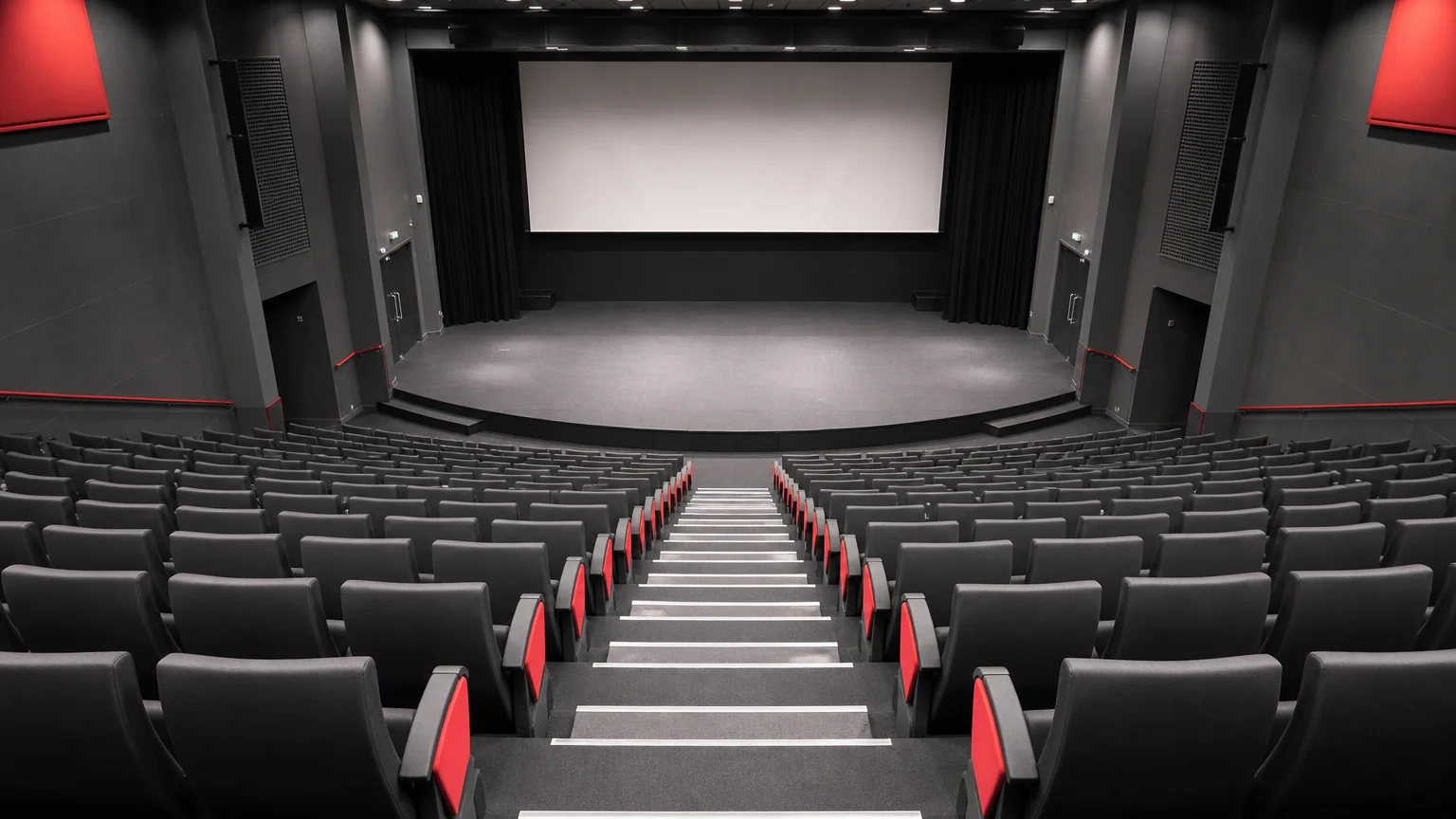 Vue plongeante sur des rangées de fauteuils de cinéma gris et noirs